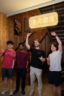 Four under the BASE sign, pointing up at it