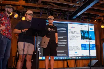 Two presenters at the screen during a demo